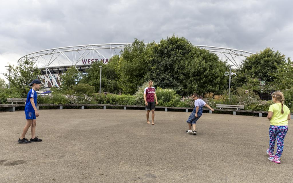 Tomáš Souček hraje fotbal s dětmi na písku před stadionem West Ham United.