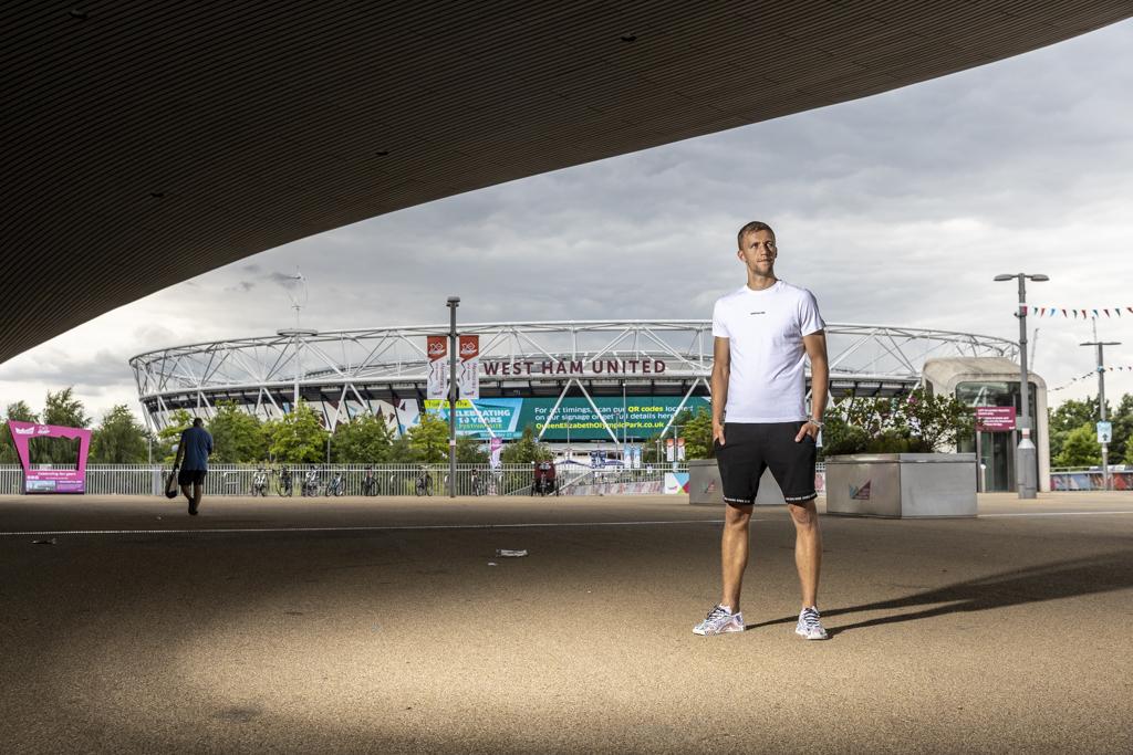 Tomáš Souček stojí v bílém tričku před stadionem londýnského klubu.