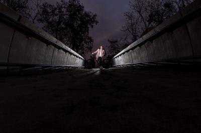Jindřiška Zemanová stojí v noci s kolem na mostě.