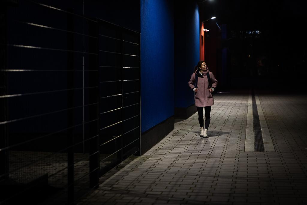 Jindřiška Zemanová prochází v tmavém večeru vedle sportovního hřiště.