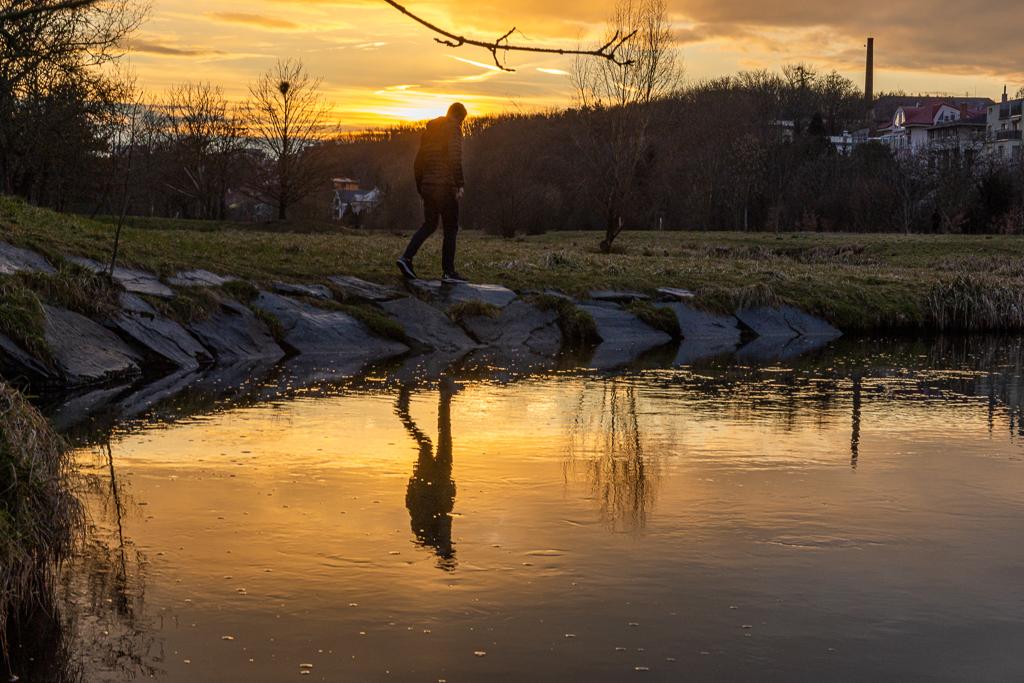 Jan Micka se prochází po kraji rybníka při západu slunce