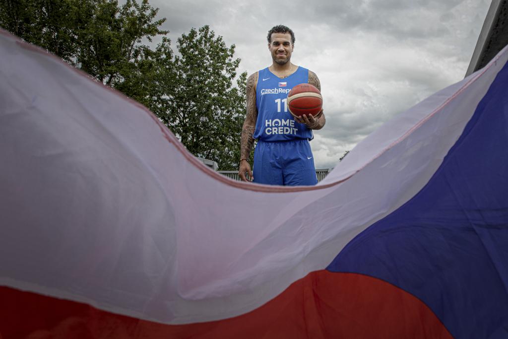 Blake Schilb stojí s basketbalovým míčem za českou vlajkou