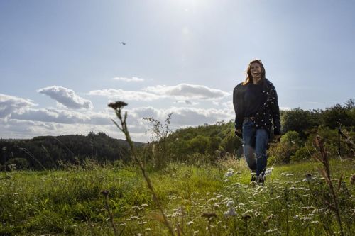 Eva Samková sedí na trávě v přírodě a rozhlíží se