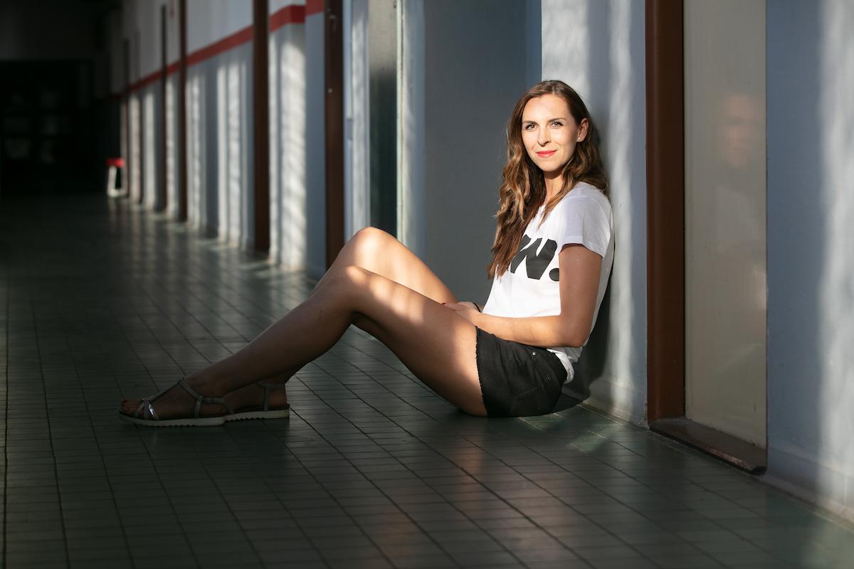 Iveta Luzumová sedí na chodbě opřená o sloup