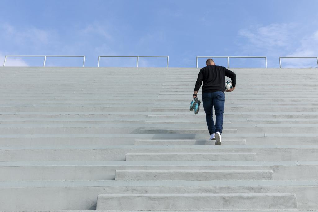 Jan Baránek jde po schodech tribuny fotbalového stadionu s míčem