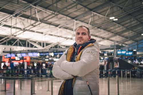 Jan Hudec v stojí olympijském oblečení se založenými rukama na letišti