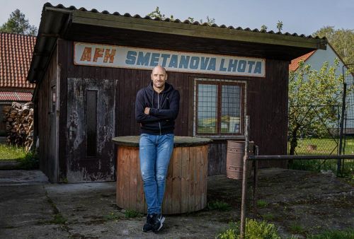 Jan Koller před malou budovou s názvem "AFK Smetanova Lhota"