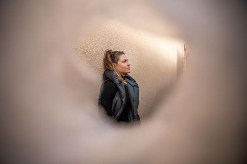 Marcela Joglová opřená o zeď s pohledem v dáli.
