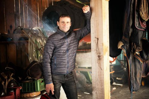 Marek Stromský se opírá o dřevěný sloup koňské stáje.
