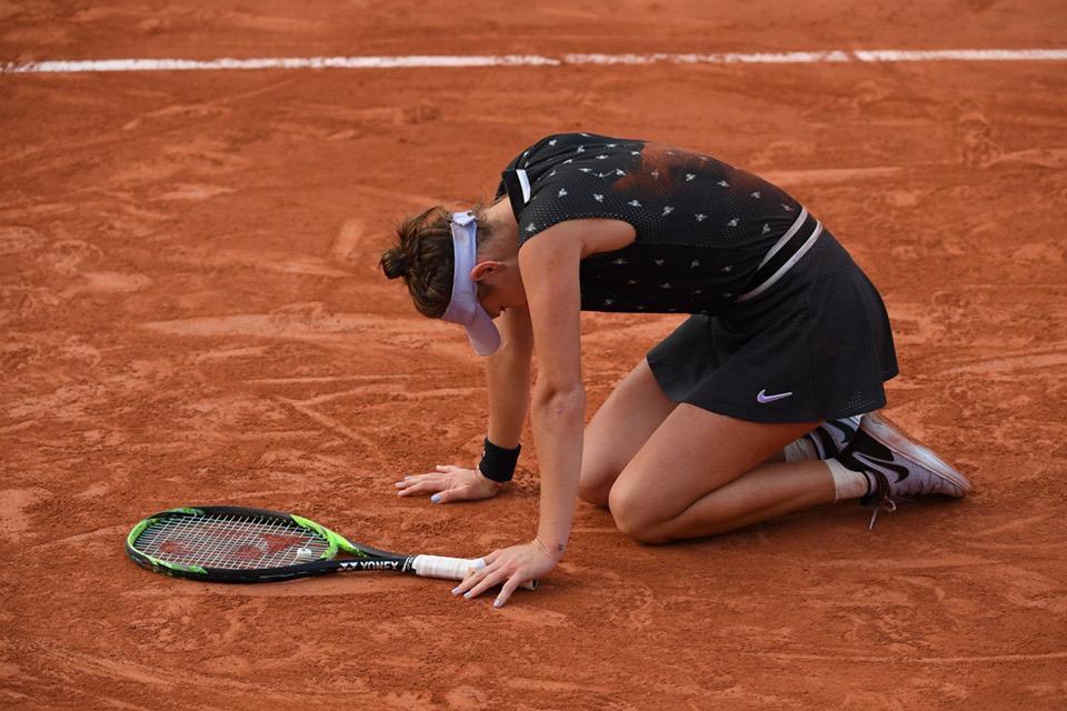 Markéta Vondroušová klečí na kurtu při zápase.