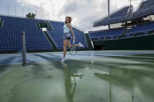 Markéta Vondroušová skáče po mokrém kurtu.