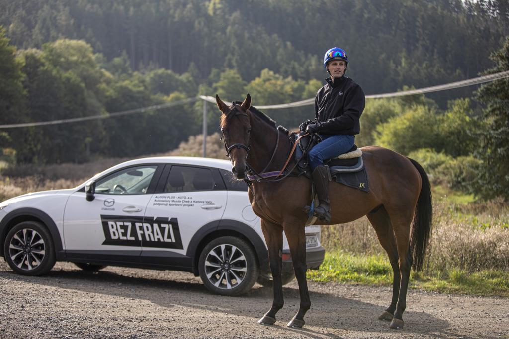 Martin Nohejl na koni vyhlížející do přírody, vedle auta Mazda s logem Bez Frází