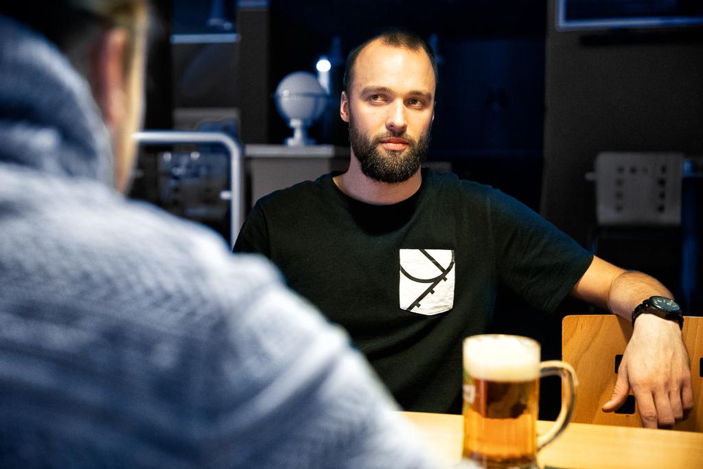 Martin Novák v rozhovoru v restauraci s pivem na stole.