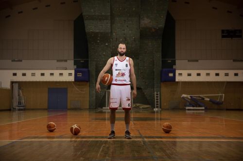 Martin Novák na palubovce obklopen basketbalovými míči.