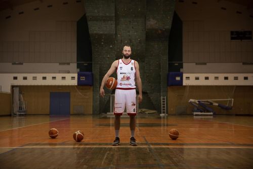 Martin Novák na palubovce obklopen basketbalovými míči.