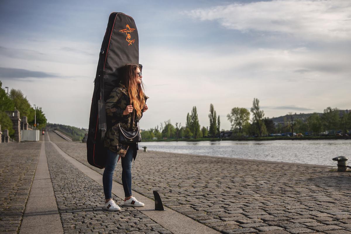 Martina Bravencová na břehu odnáší svůj surf k vodě.