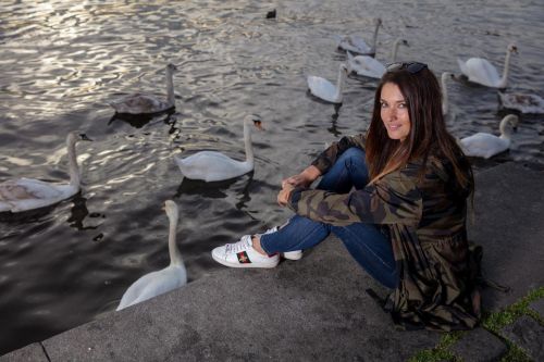 Martina Bravencová sedí u vody a krmí labutě.