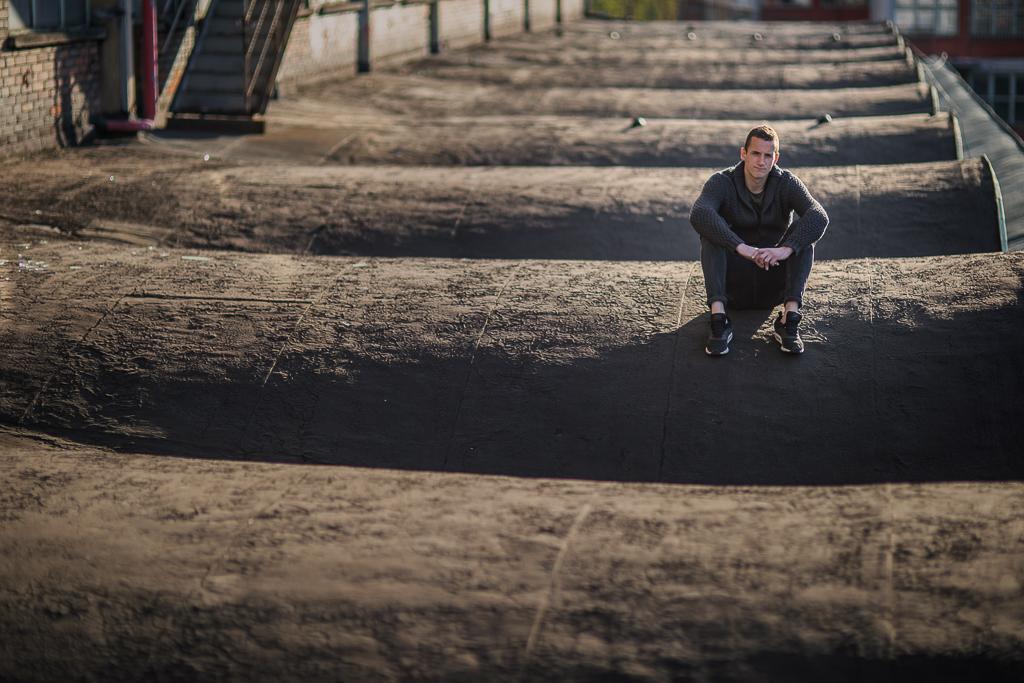 Matej Rakovan sedí na zemi v terénu.