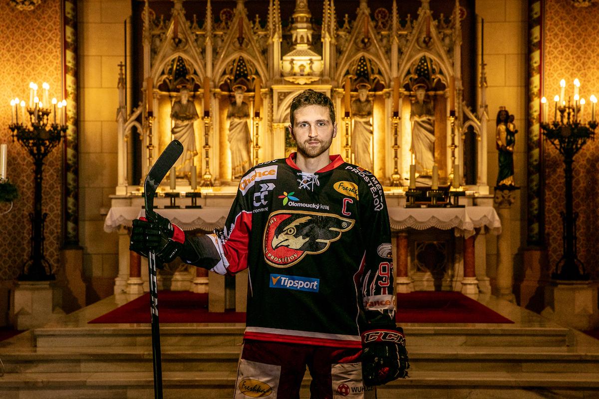 Matouš Maxmilián Venkrbec stojí v hokejovém a s hokejkou v ruce v kostele.