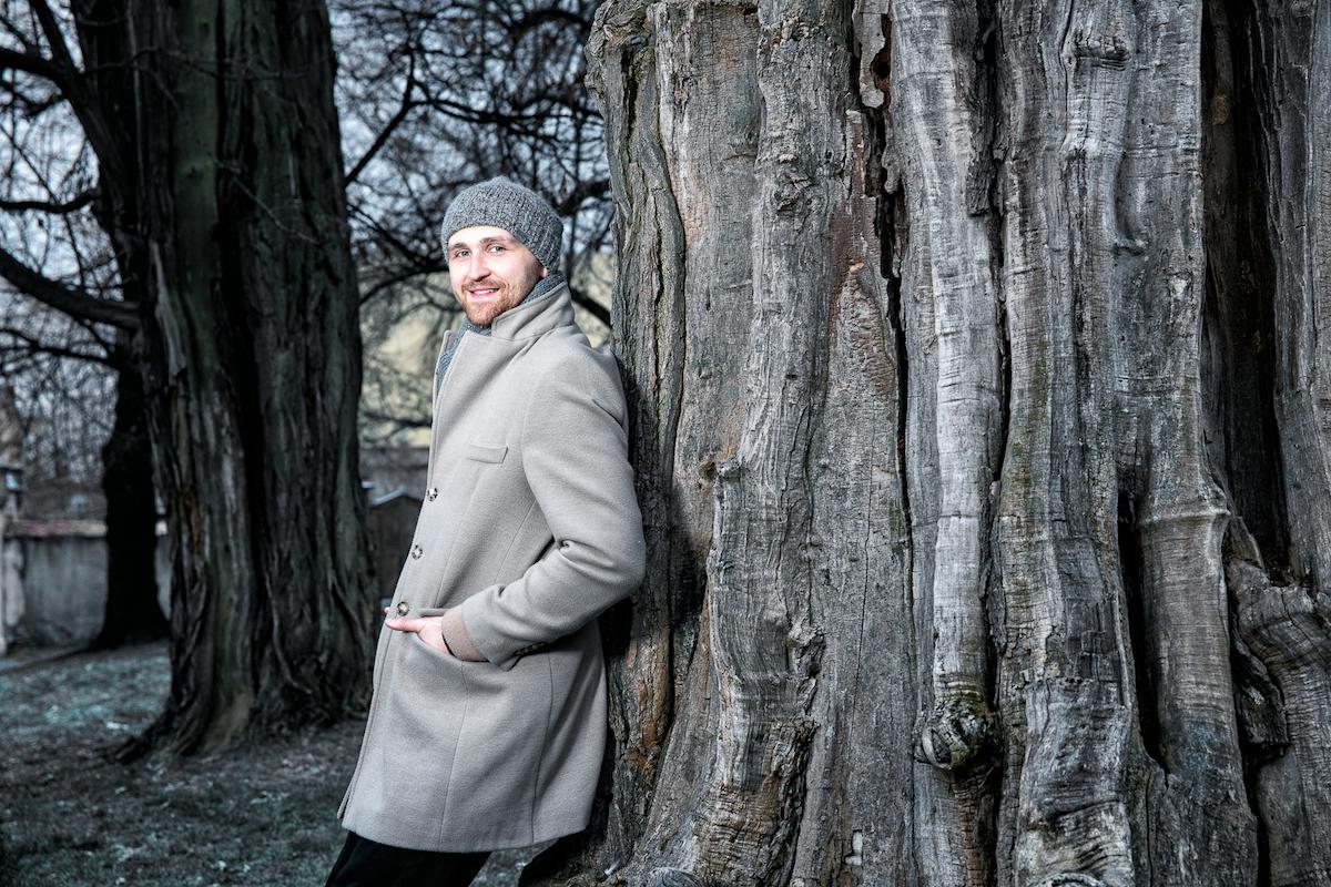 Matouš Maxmilián Venkrbec se opírá o strom venku.