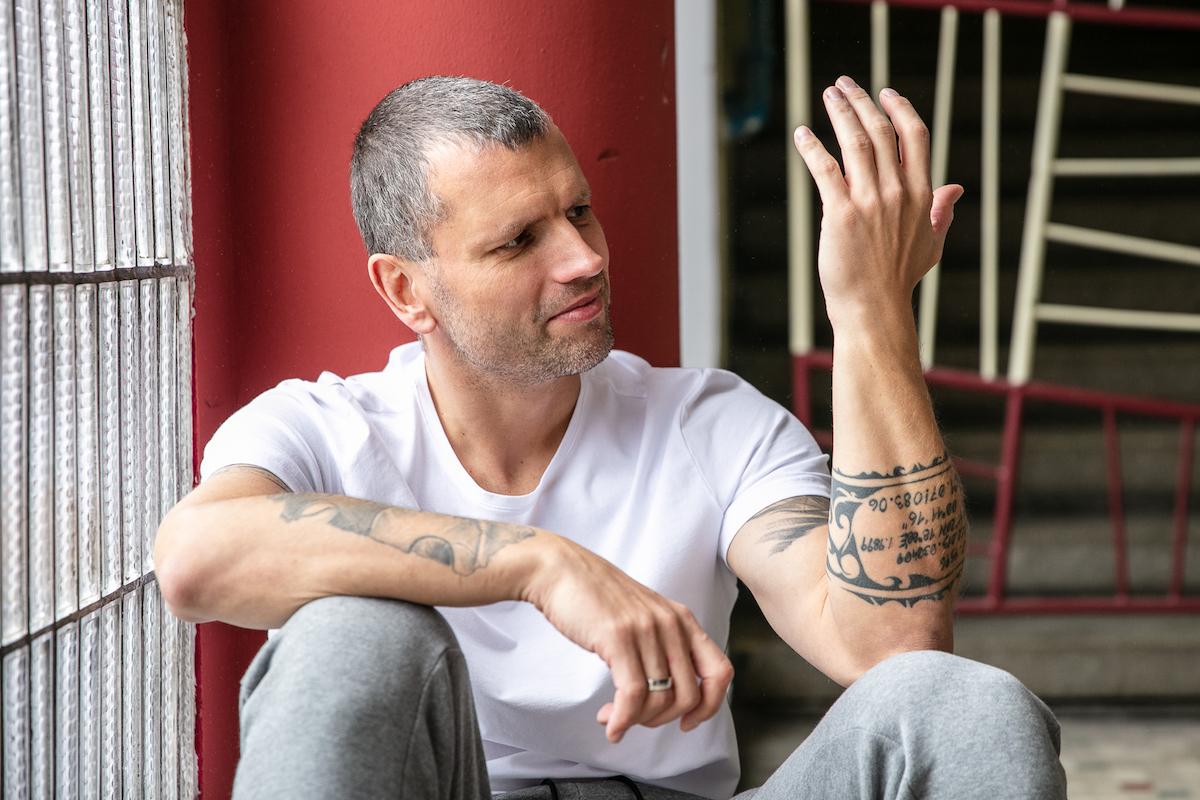 Michal Broš se dívá na svou ruku s tetováním.