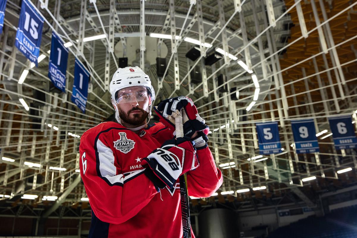 Michal Kempný opřený o hokejku stojí pod výrazným stropem areny.
