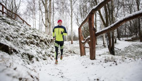 Miloš Škorpil běží v lese po zasněžené cestě.