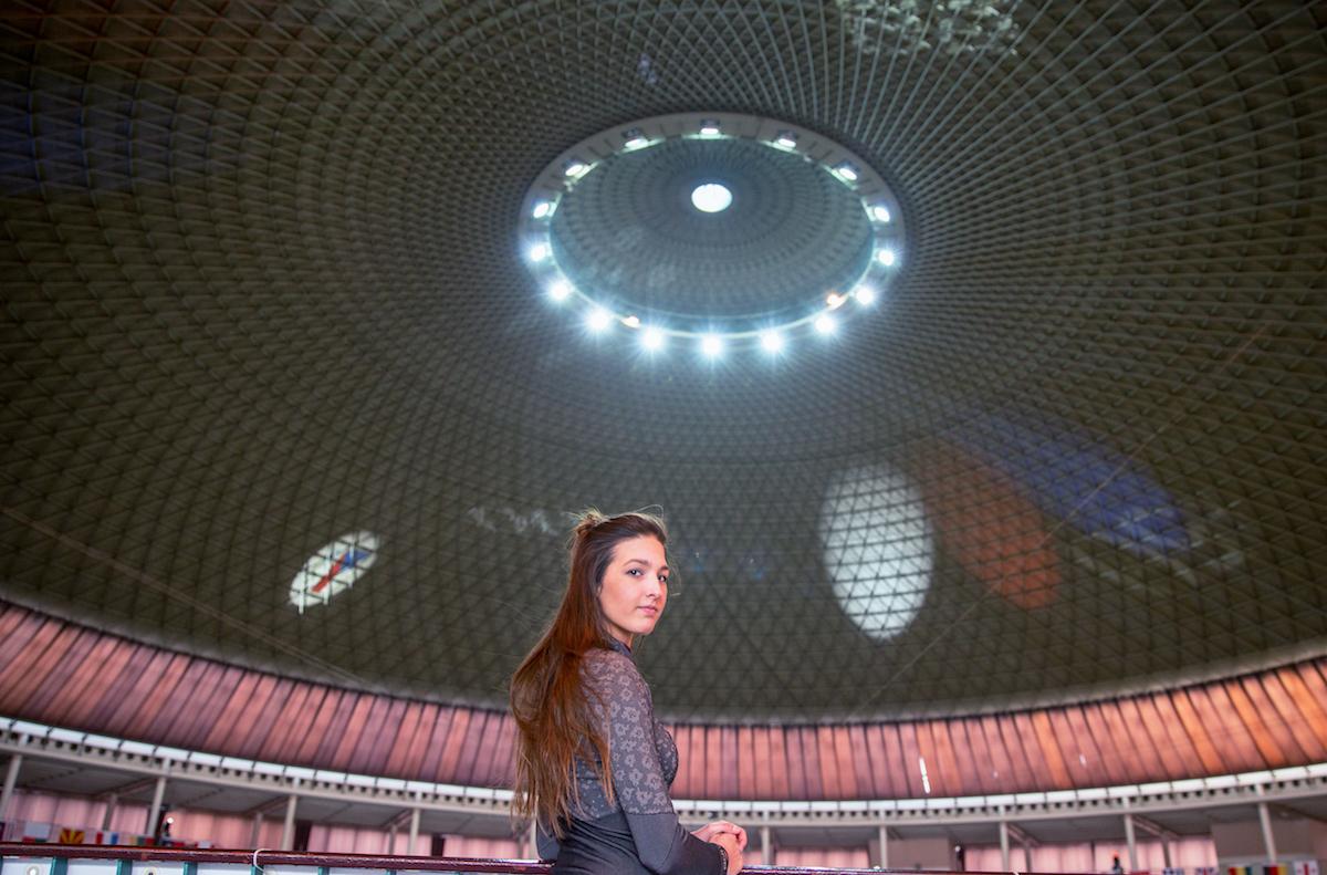 Monika Míčková se ohlíží za sebe stojící ve sportovní hale.