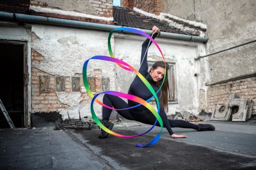 Monika Míčková cvičí s barevnou stuhou na střeše domu.