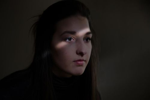 Monika Míčková na tmavé fotografii s proužkem světla přecházejícím přes její obličej.