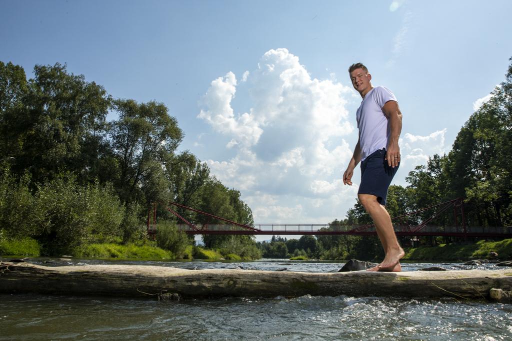 Ondřej Palát v přírodě přechází přes tekoucí potok.