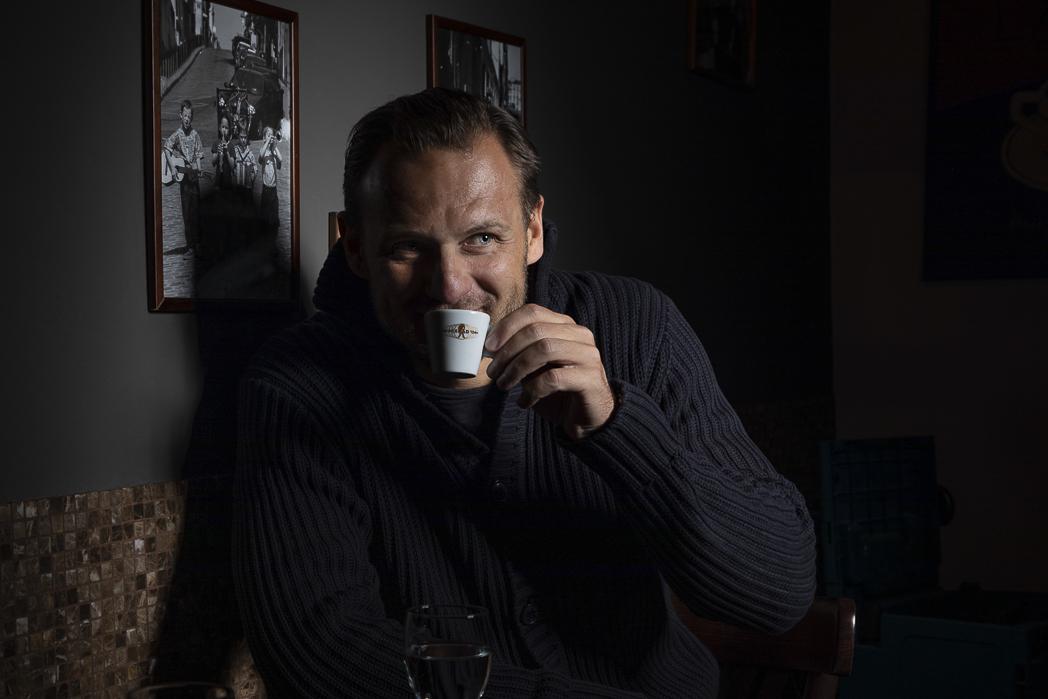 Pavel Brendl opřený o zeď usrkává z kávy.