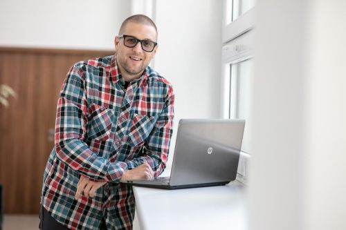 Petr Málek se opírá o parapet a má před sebou notebook