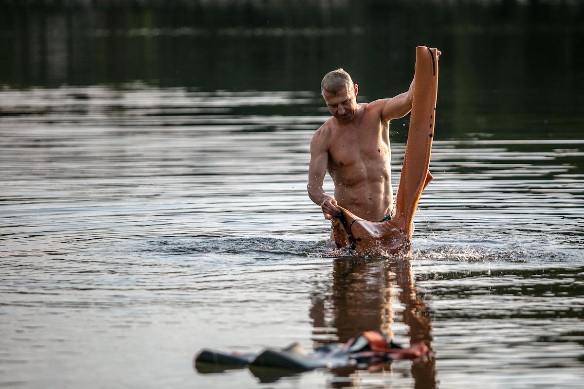 Petr Vabroušek si myje sportovní oblečení v jezeře.