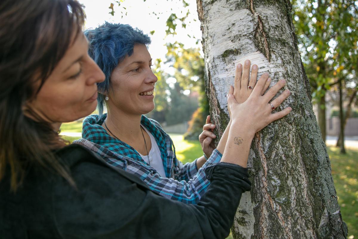 Petra Nová se společně s partnerkou drží stromu.