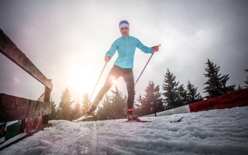 Petra Nováková běží na lyžích se sluncem v zádech.