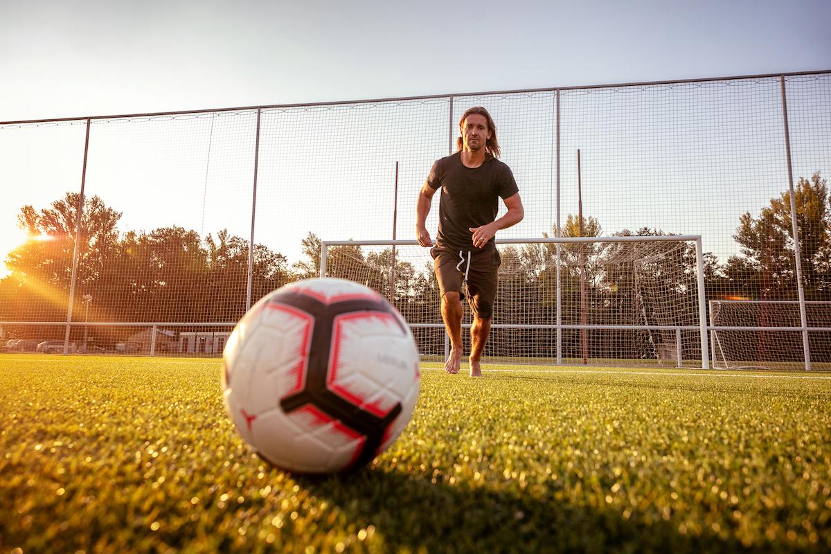 Radim Ottmar běží na fotbalovém trávníku za míčem při zápasu slunce.