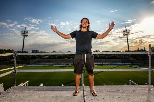 Radim Ottmar se svým gestem na tribuně fotbalového stadionu, s trávníkem v zádech.