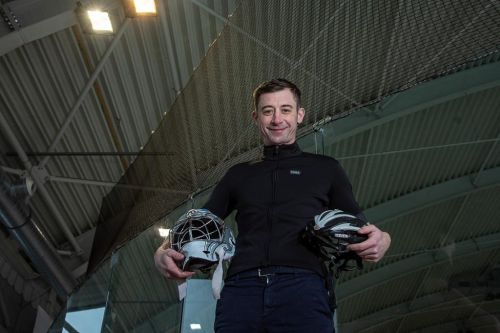 Radomír Šimůnek stojí v hokejové hale cyklistickou a hokejovou helmou