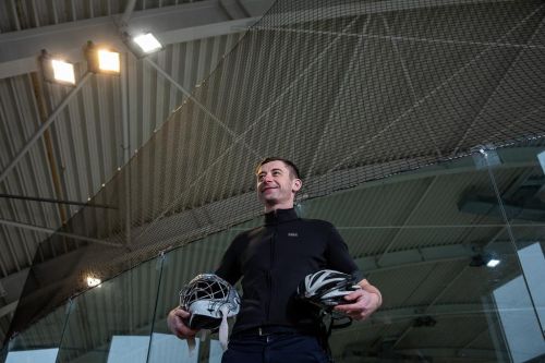 Radomír Šimůnek stojí v hokejové hale cyklistickou a hokejovou helmou