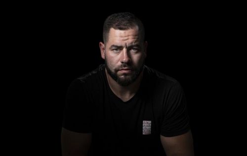 Portrétní fotografie Romana Poláka na černém pozadí.