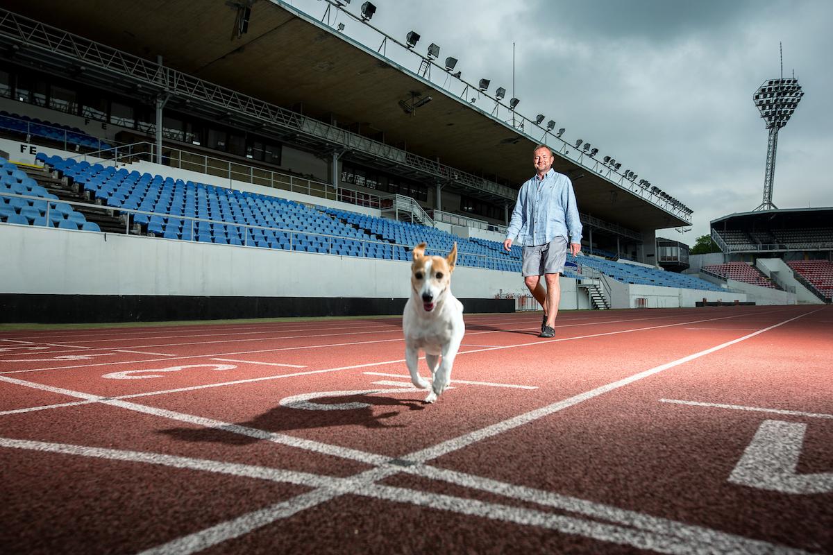 Tomáš Dvořák se svým psem běžícím po atletickém stadionu.