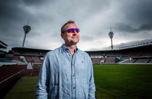 Tomáš Dvořák ve svých brýlích s atletickým stadionem na pozadí.