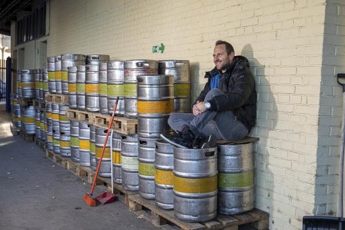 Tomáš Jun sedí na sudech s pivem.