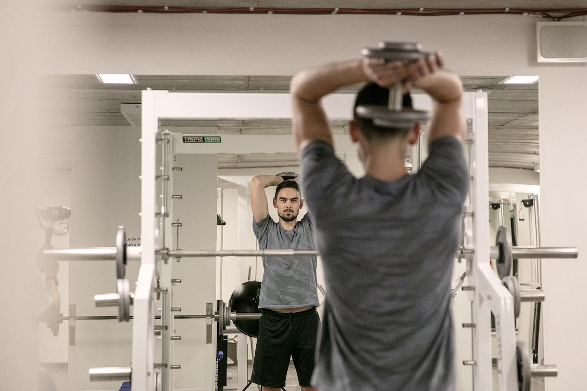 Tomáš Satoranský cvičí s činkami před zrcadlem.